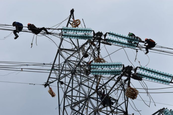 Caption: Pekerja melakukan perbaikan jaringan SUTET di kawasan PIER. Keberadaan program BPJS diyakini membuat pekerja merasa lebih terjamin dan terlindungi.