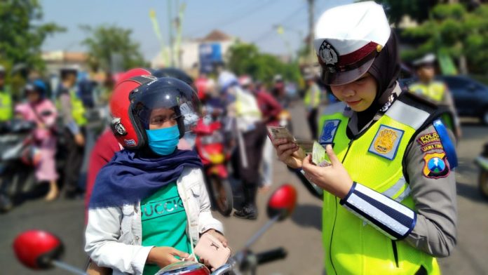 Seorang petugas saat memeriksa kelengkapan surat pengendara motor di jalan raya seputar Alun-alun Bangil, Kabupaten Pasuruan, Kamis (5/9/2019).
