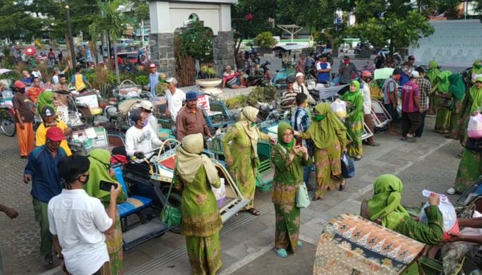TERTIB: Para abang becak berbaris rapi sambil menerima bantuan sembako dari para pengurus PAC Muslimat NU Bangil