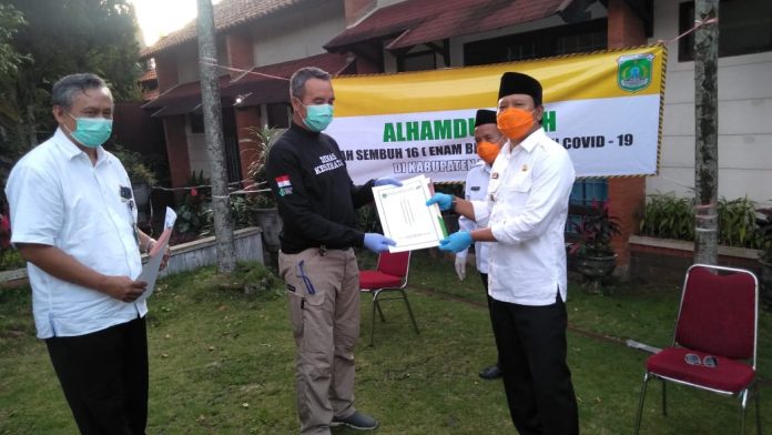 Bupati Pasuruan Irsyad Yusuf saat memberikan surat keterangan sehat kepada pasien yang sembuh dari Covid-19 di halaman hotel Permata Biru.
