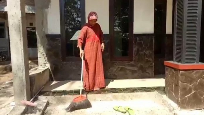 Seorang warga di Desa Capang, Kecamatan Purwodadi, Kabupaten Pasuruan mencoba membersihkan ulat bulu di beranda rumah, Senin (24/6/2019).